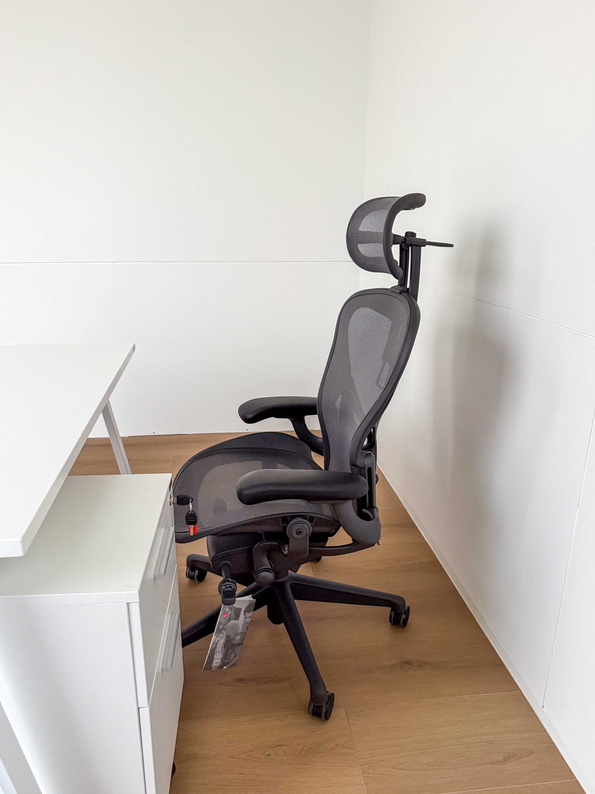 Ergonomic chair with headrest beside a desk in a bright office